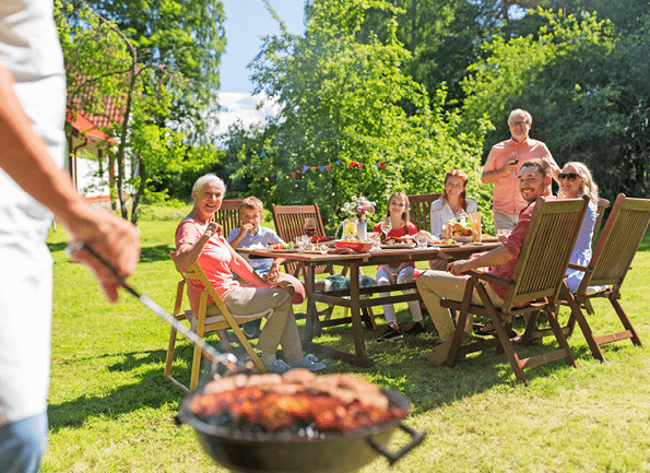 food, people and family time concept - man cooking meat on barbecue grill at summer garden party
