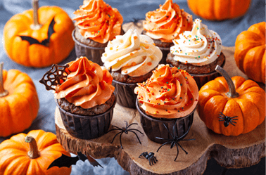 Halloween cupcakes and pumpkins on wooden background. Sweets for holiday party.