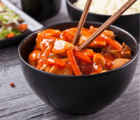 Chinese chicken sweet and sour sauce, served with rice and vegetables on woodboard