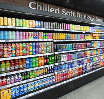 A store with a cooler section that has many drinks in it. Description generated by AI