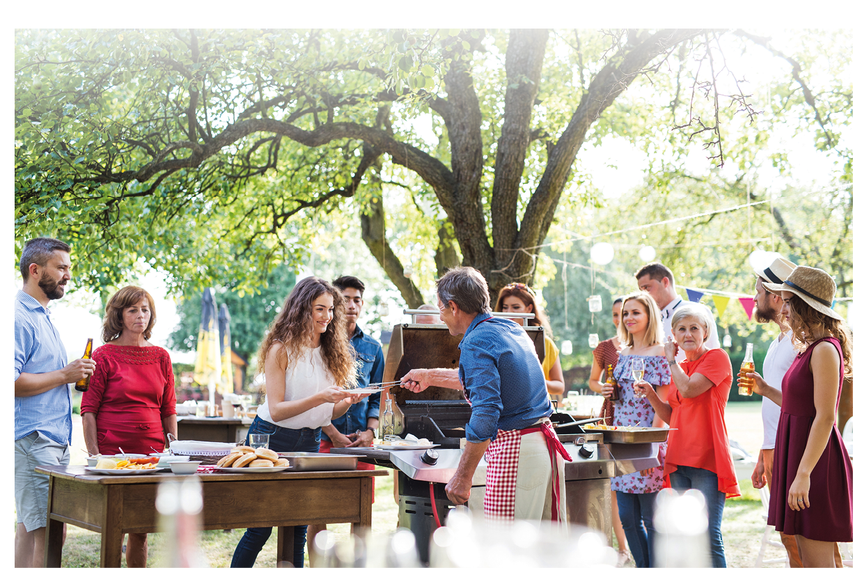 A group of people standing around a table with food. Description generated by AI