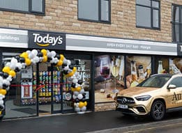 A gold car is parked outside of a store. Description generated by AI