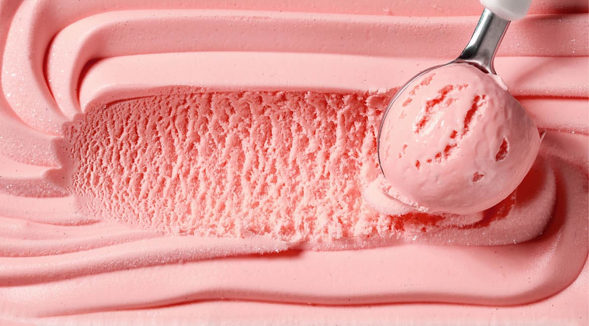 A spoon is scooping pink ice cream. Description generated by AI