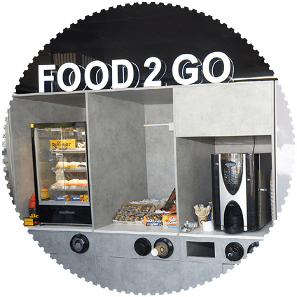A man standing in a store with a food and drinks section. Description generated by AI