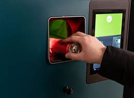 A person is putting a key into a slot on a blue wall. Description generated by AI