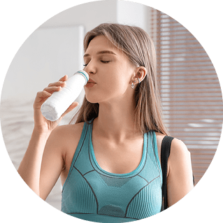 A woman drinking a white liquid from a bottle. Description generated by AI