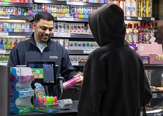 A man is smiling at a cashier. Description generated by AI