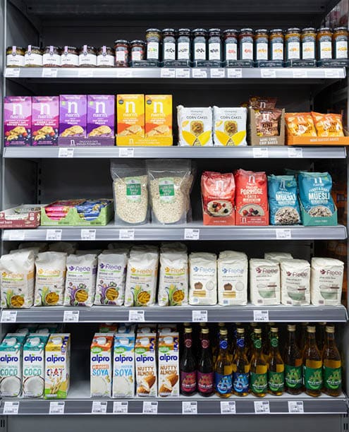 A store shelf with a variety of food items, including bottles of beer. Description generated by AI