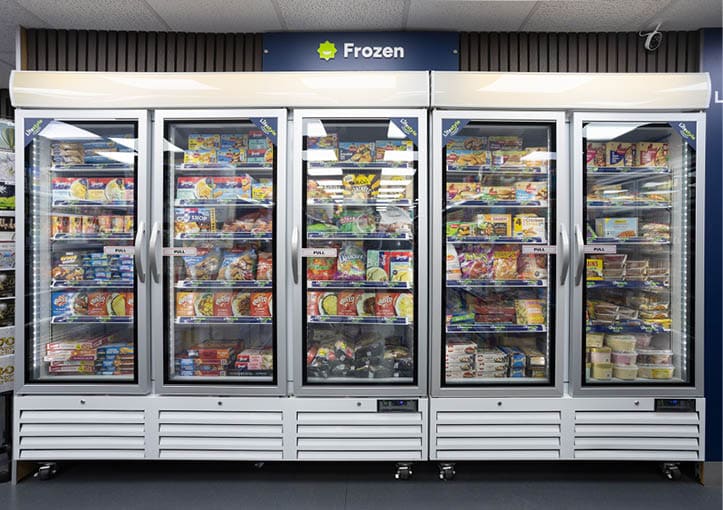 A supermarket freezer section with five glass doors filled with various frozen food products neatly arranged on shelves. Description generated by AI