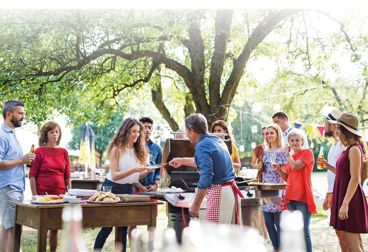 A group of people standing around a table with food. Description generated by AI