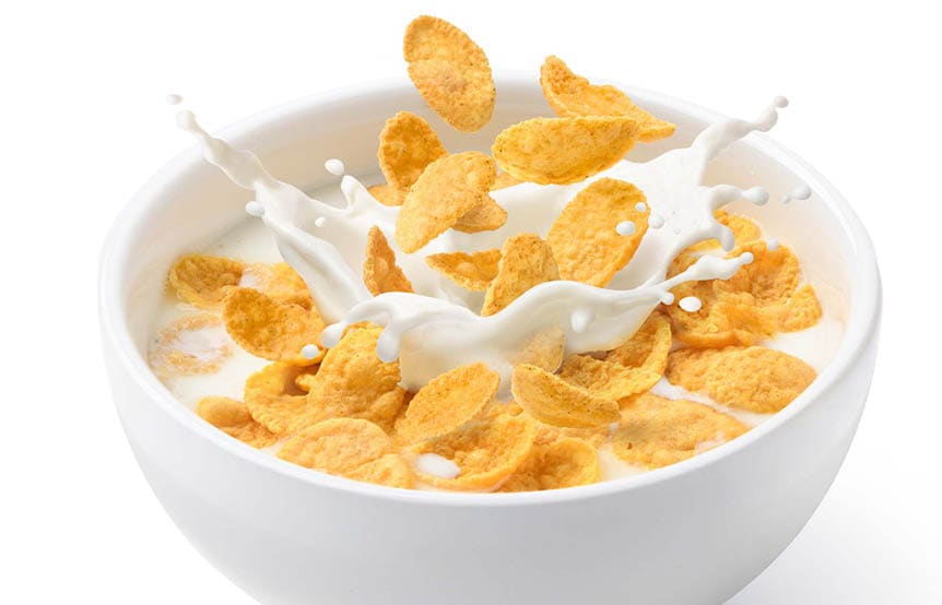 Corn flakes with milk splash in white bowl isolated on white background.