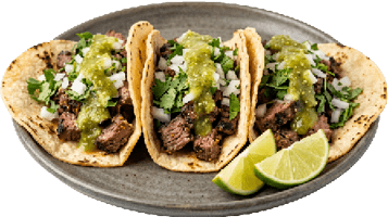 Three tacos filled with grilled meat, chopped onions, cilantro, and green salsa are served on a plate with lime wedges. Description generated by AI