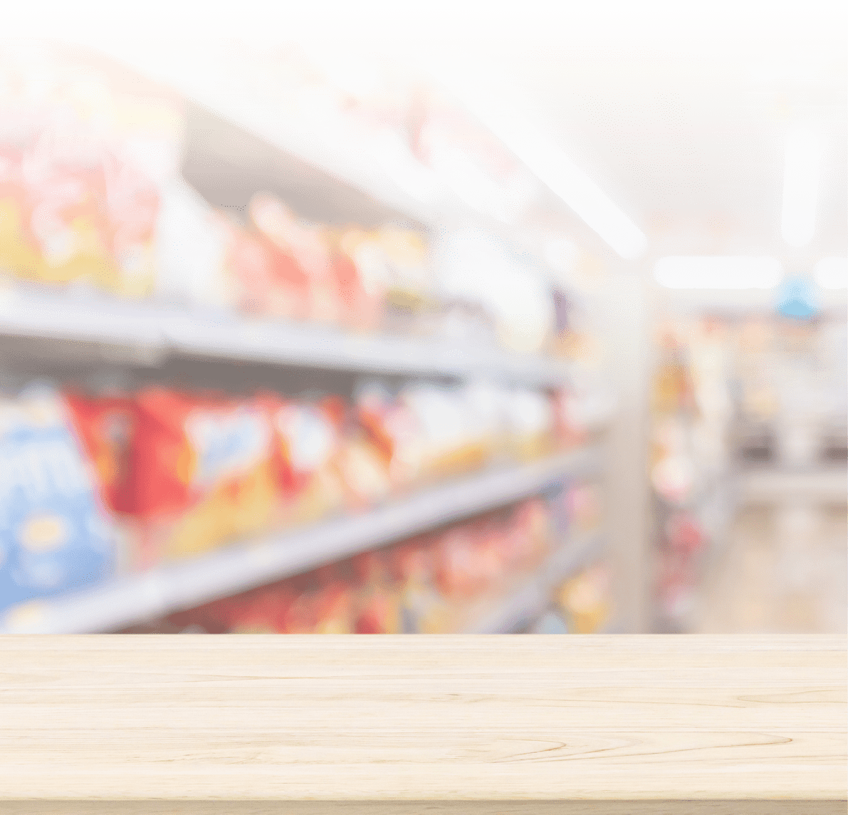 A wooden tabletop in focus with blurred supermarket aisles filled with various products in the background. Description generated by AI