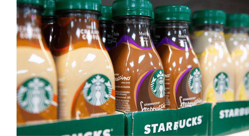 Bottles of Starbucks Frappuccino coffee drinks are arranged in a row on a store shelf. Description generated by AI