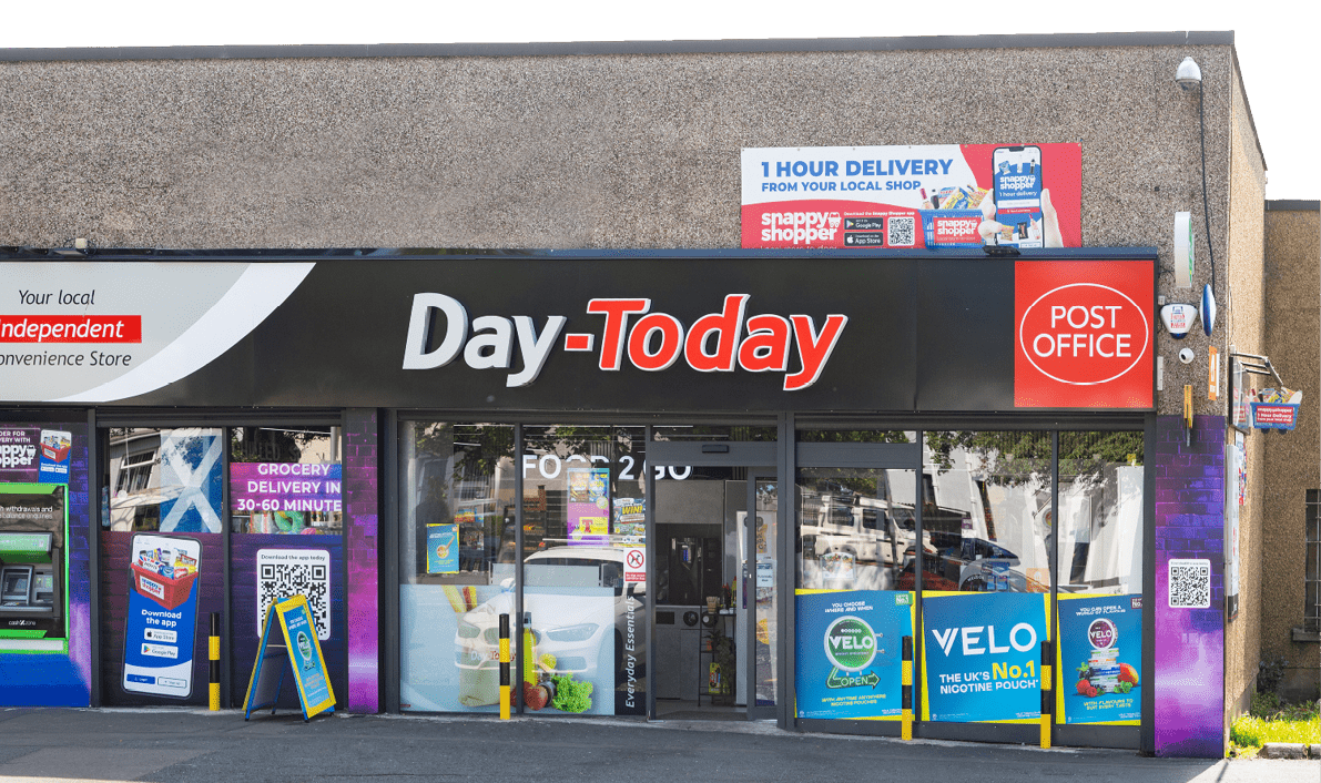 A storefront of a convenience store named Day-Today with a black and red sign, glass doors, and various advertisements for grocery delivery and nicotine pouches. Description generated by AI